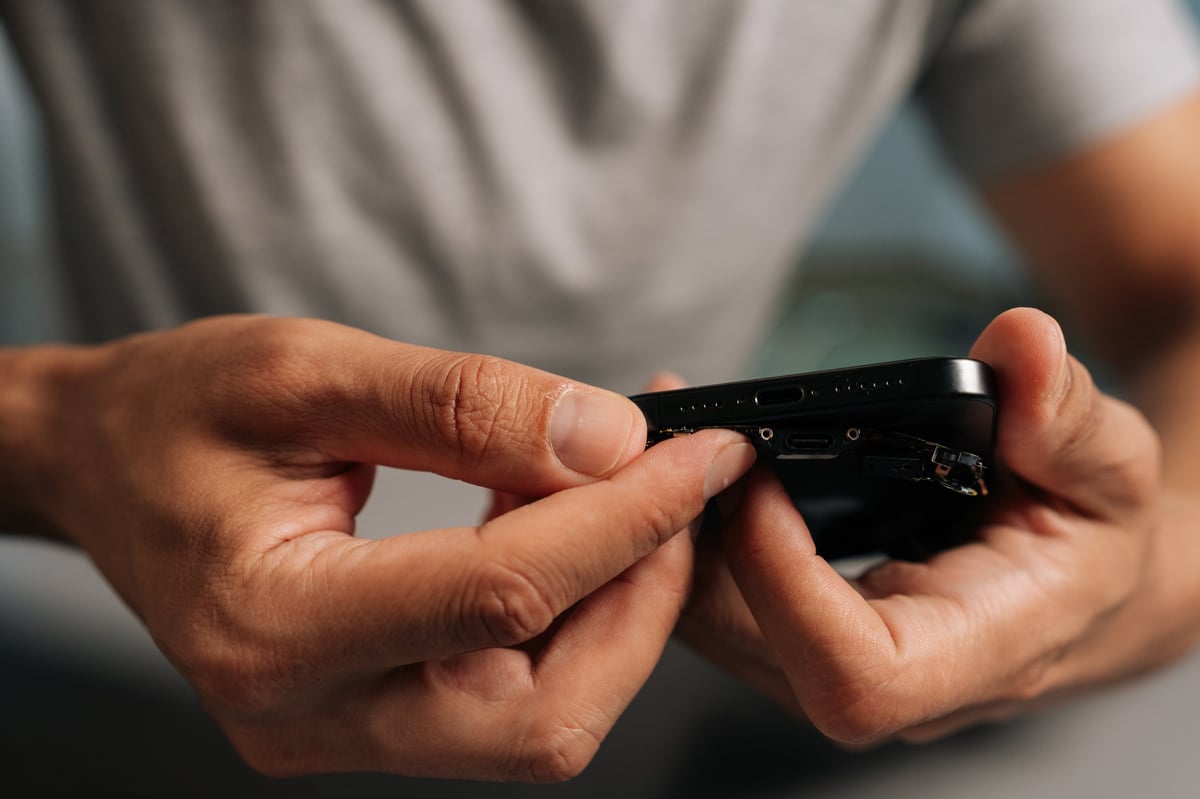 Närbild av en tekniker som inspekterar en felaktig mobilkontakt